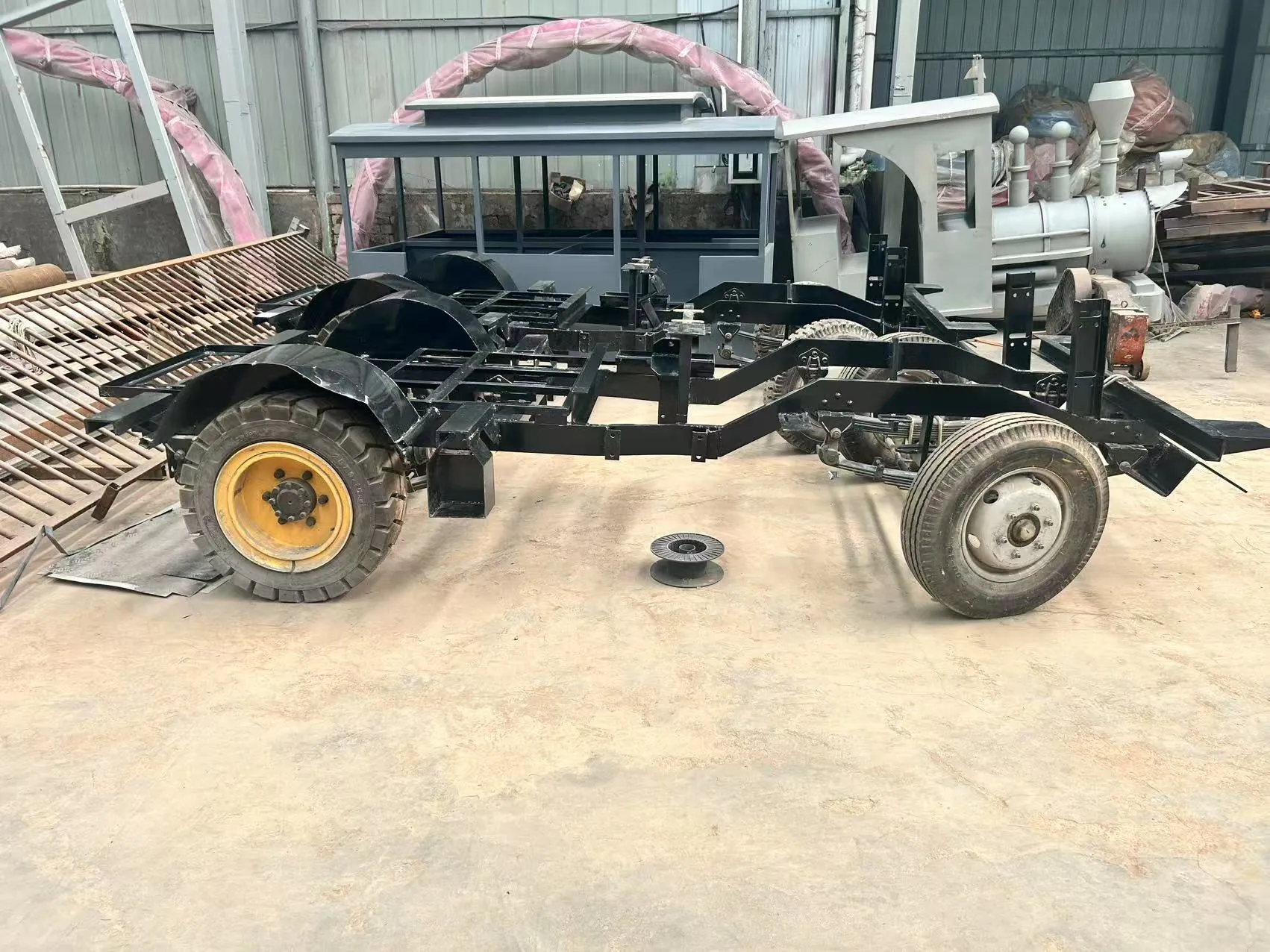Trackless vs Track Train: Specs, Costs & How to Choose Welded steel chassis of a trackless sightseeing train carriage on road wheels in the workshop